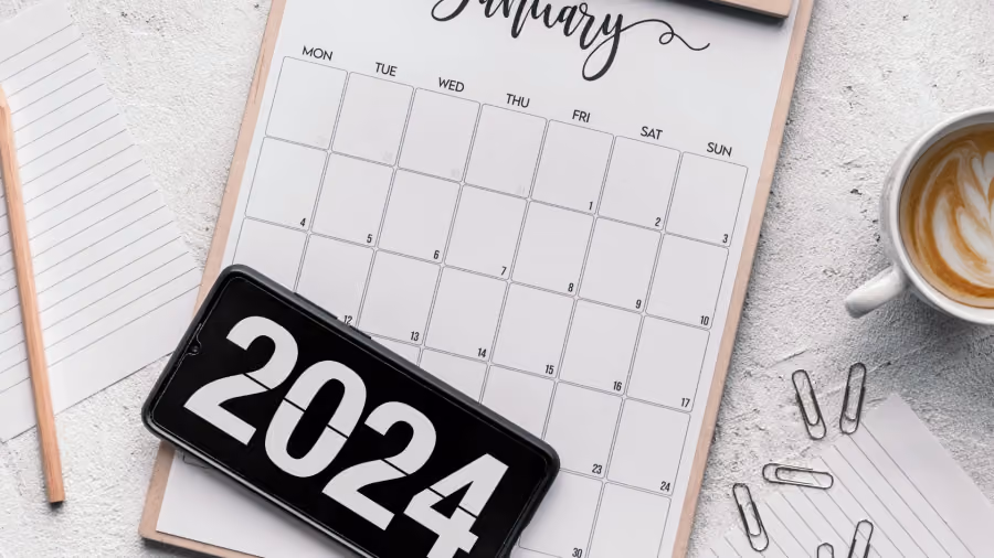 Foto de calendário de mesa em prancheta com um celular exibindo o número 2024 sobre ele, xícara de café e clipes ao redor