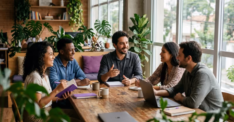 Fundador de uma pequena empresa conversando com a equipe em volta de uma mesa