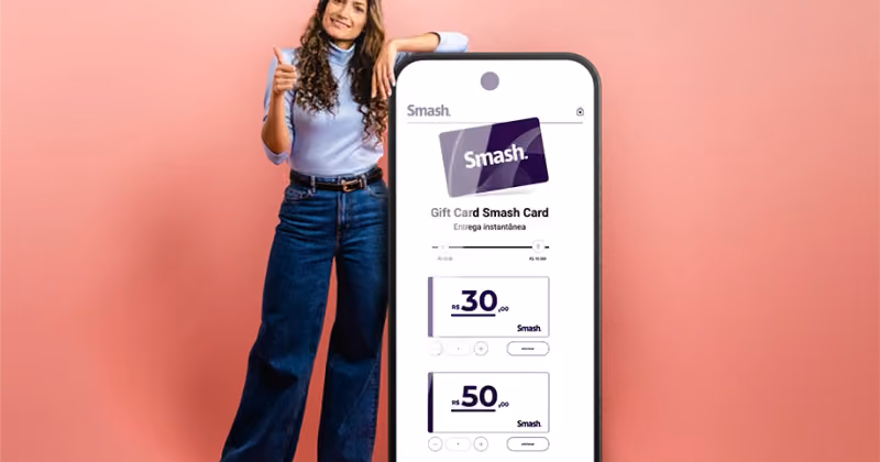 Foto de mulher com o polegar erguido apoiada em um celular gigante que exibe a página de compra do Smash Card, em fundo rosa
