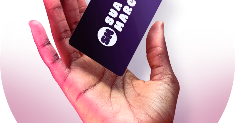 Foto de mão aberta segurando um cartão roxo escuro com a inscrição sua marca e um logotipo genérico, sobre fundo rosa